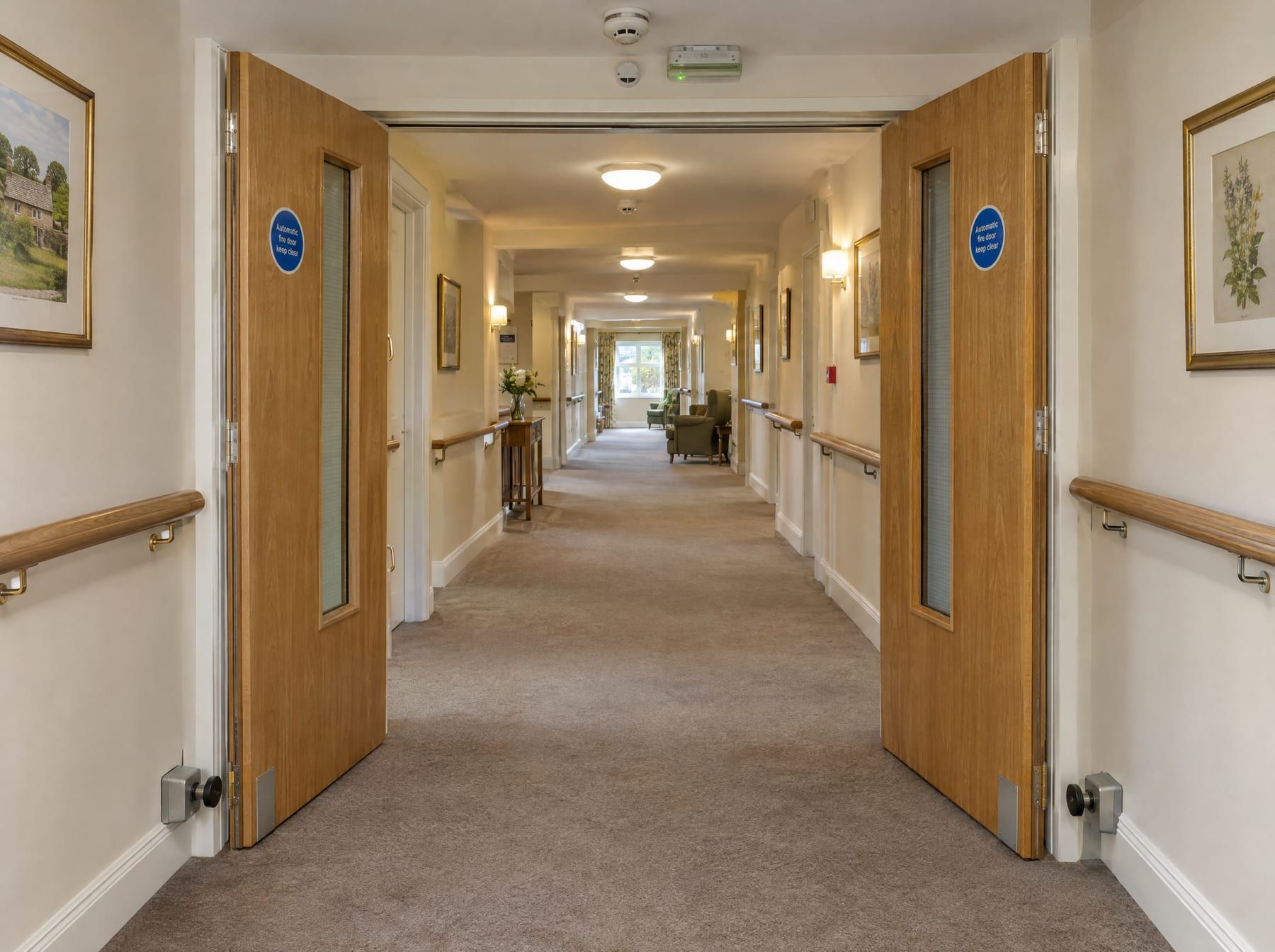 Care home corridor with handrails and fire doors on hold-open devices